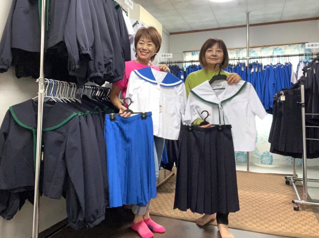 笑びん協力店「安慶田店」の中で学生服を紹介する笑びんの店主と店舗スタッフ